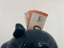 Zwei Geldscheine gucken zur Hälfte aus einem Sparschwein heraus