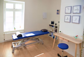 Heller Physiotherapieraum mit Behandlungsliege und Physiotherapie Equipment.